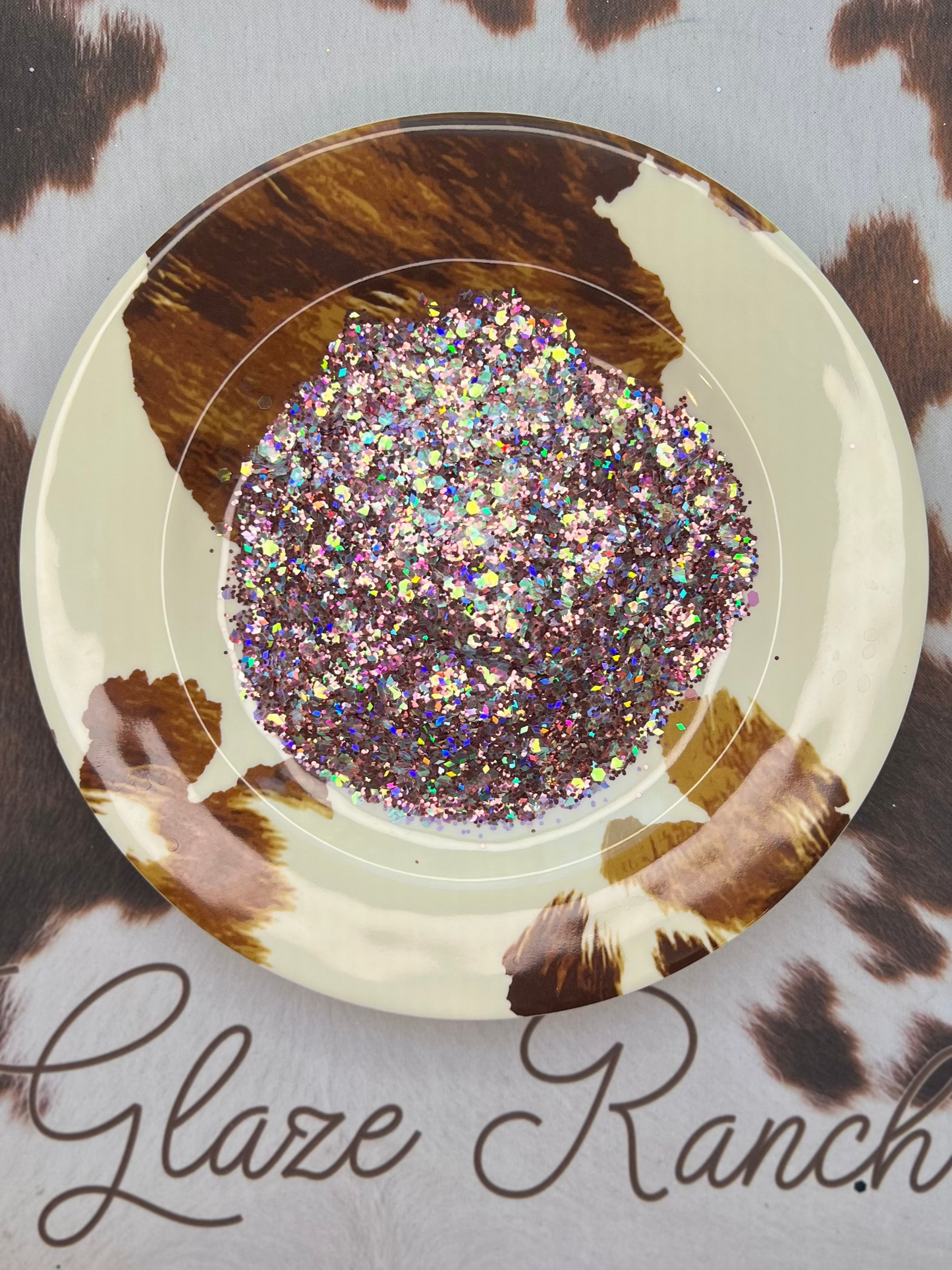 Decorative plate with glittery center on a cow print background with 'Glaze Ranch' branding.