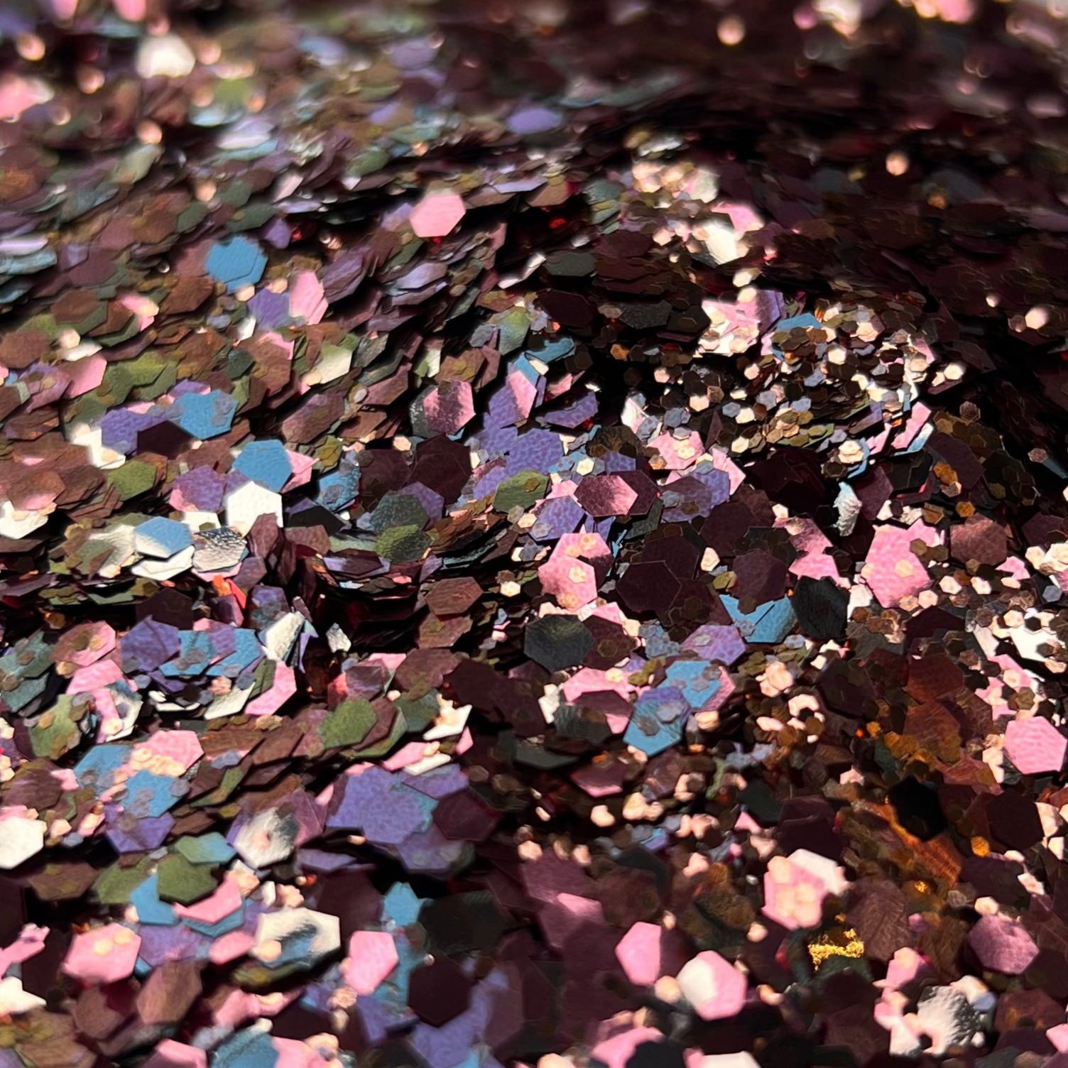 Colorful glitter in a white dish on a surface with a blurred background