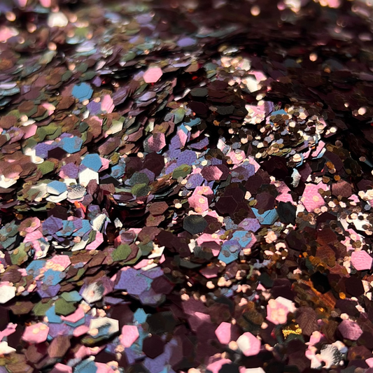 Colorful glitter in a white dish on a surface with a blurred background