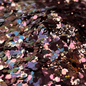 Colorful glitter in a white dish on a surface with a blurred background