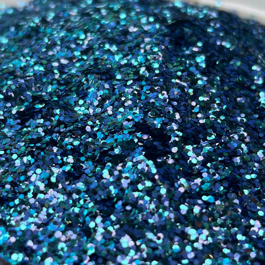 Blue glitter in a white dish on a patterned surface