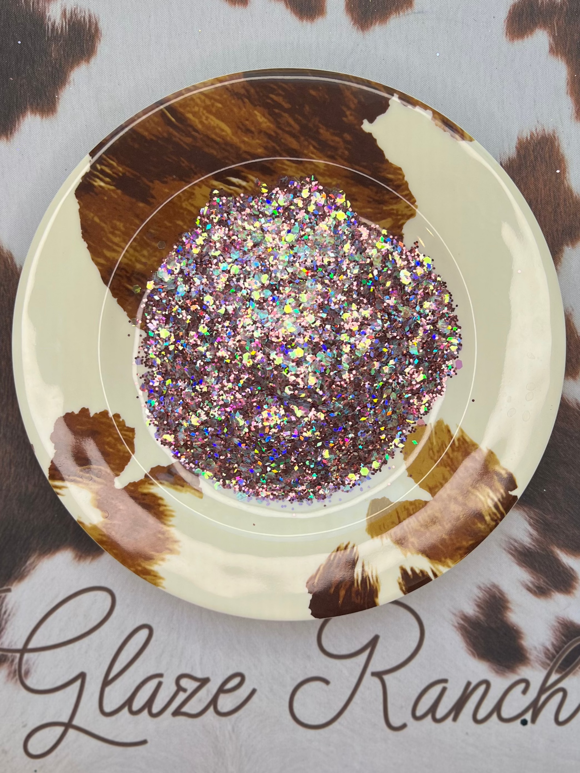 Decorative plate with glittery center on a cow print background with 'Glaze Ranch' branding.