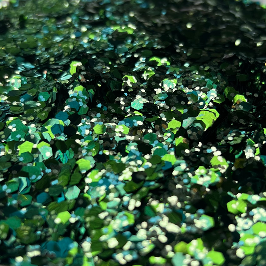 Green glitter in a white container on a brown and white surface