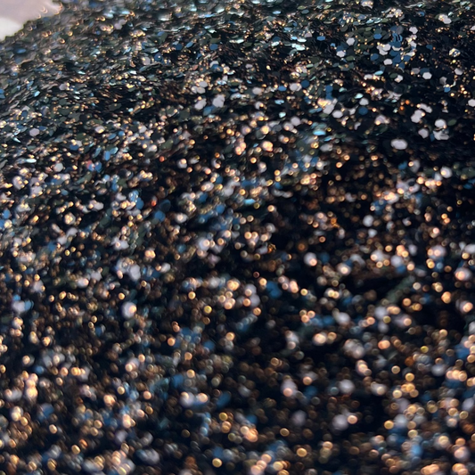 Close-up of black and copper glitter in a bowl with a blurred background