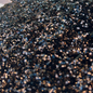 Close-up of black and copper glitter in a bowl with a blurred background