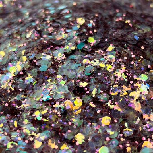 Multicolored glitter on a white plate with a brown surface underneath